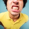 Man in a yellow shirt grinding his teeth